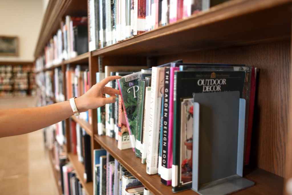 A photo of a hand pulling a book off a full bookshelf